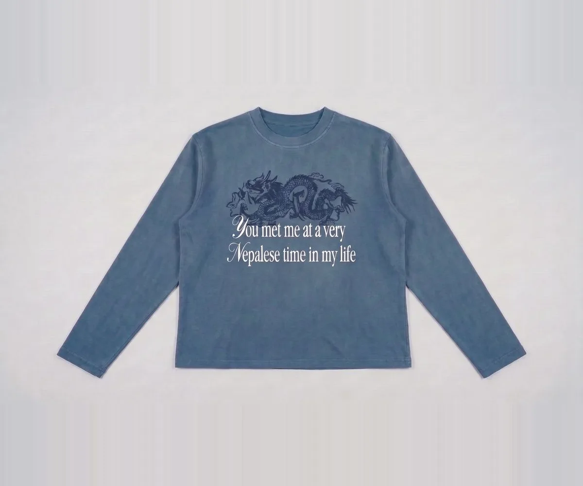 Front view of the dusty blue longsleeve showing the dragon print and the words "You met me at a very Nepalese time in my life"