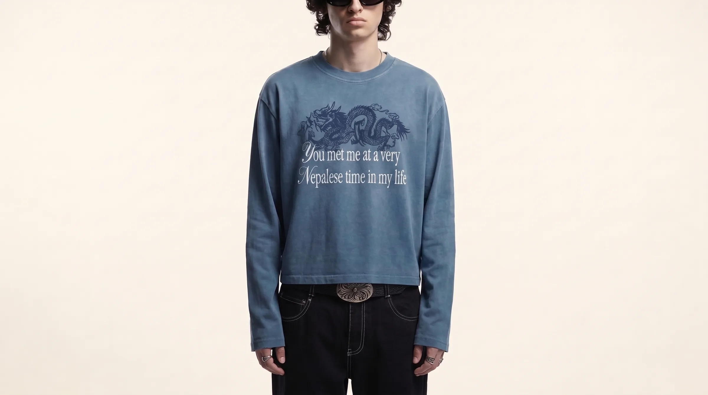 Model wearing the dusty blue boxy longsleeve with a navy dragon print and the words "You met me at a very Nepalese time in my life"